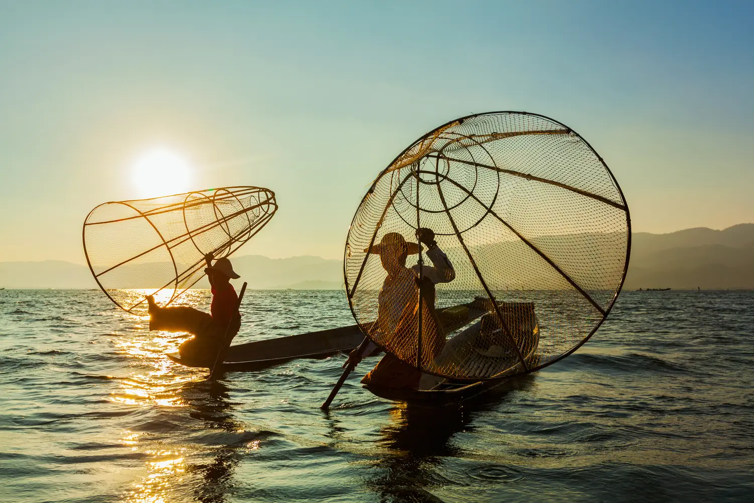 A lone fisherman casting a net from a wooden boat on a still lake at golden hour
