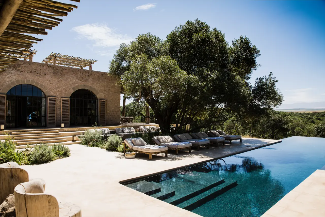 A Mediterranean villa with a long infinity pool framed by cypress and olive trees